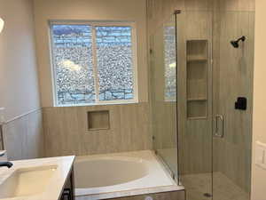 Bathroom featuring a bath, vanity, and a shower stall