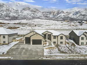 View of front facade with a garage, a mountain view, concrete driveway, and stone siding