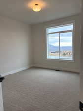 Empty room with light colored carpet and a mountain view