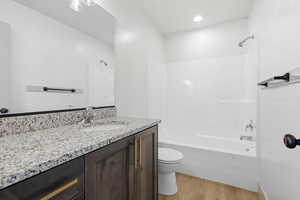 Bathroom with vanity, light wood finished floors, shower / washtub combination, and recessed lighting