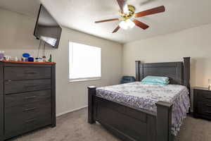 Bedroom with light carpet, a ceiling fan, and a textured ceiling