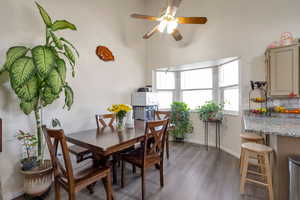 Dining space with dark wood-style flooring and a ceiling fan