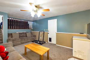 Living room featuring a ceiling fan, a textured ceiling, and carpet floors
