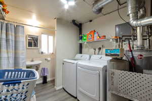 Laundry area featuring light wood finished floors and independent washer and dryer