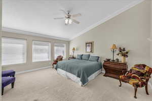 Bedroom with vaulted ceiling, carpet floors, ornamental molding, and a ceiling fan