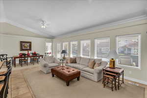 Living room featuring vaulted ceiling, a ceiling fan, and light tile patterned floors