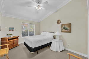 Carpeted bedroom with lofted ceiling, crown molding, and a ceiling fan