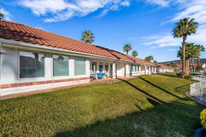 Rear view of house featuring a patio, a yard, a tiled roof, and stucco siding