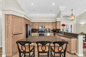 Kitchen featuring a kitchen breakfast bar, stainless steel appliances, a peninsula, decorative backsplash, and dark stone counters