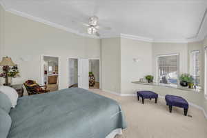Bedroom with a spacious closet, carpet floors, a ceiling fan, crown molding, and ensuite bath
