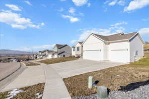 View of side of home featuring concrete driveway, a residential view, and an attached garage