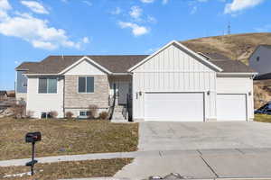 View of front facade featuring board and batten siding, concrete driveway, and a shingled roof