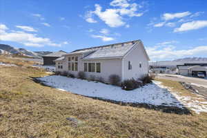 Snow covered rear of property featuring a mountain view and a lawn