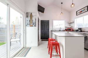 Kitchen with a kitchen breakfast bar, white cabinetry, dishwasher, lofted ceiling, and a kitchen island