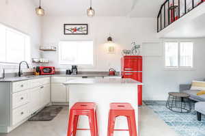 Kitchen with white cabinetry, light countertops, finished concrete floors, open shelves, and a center island