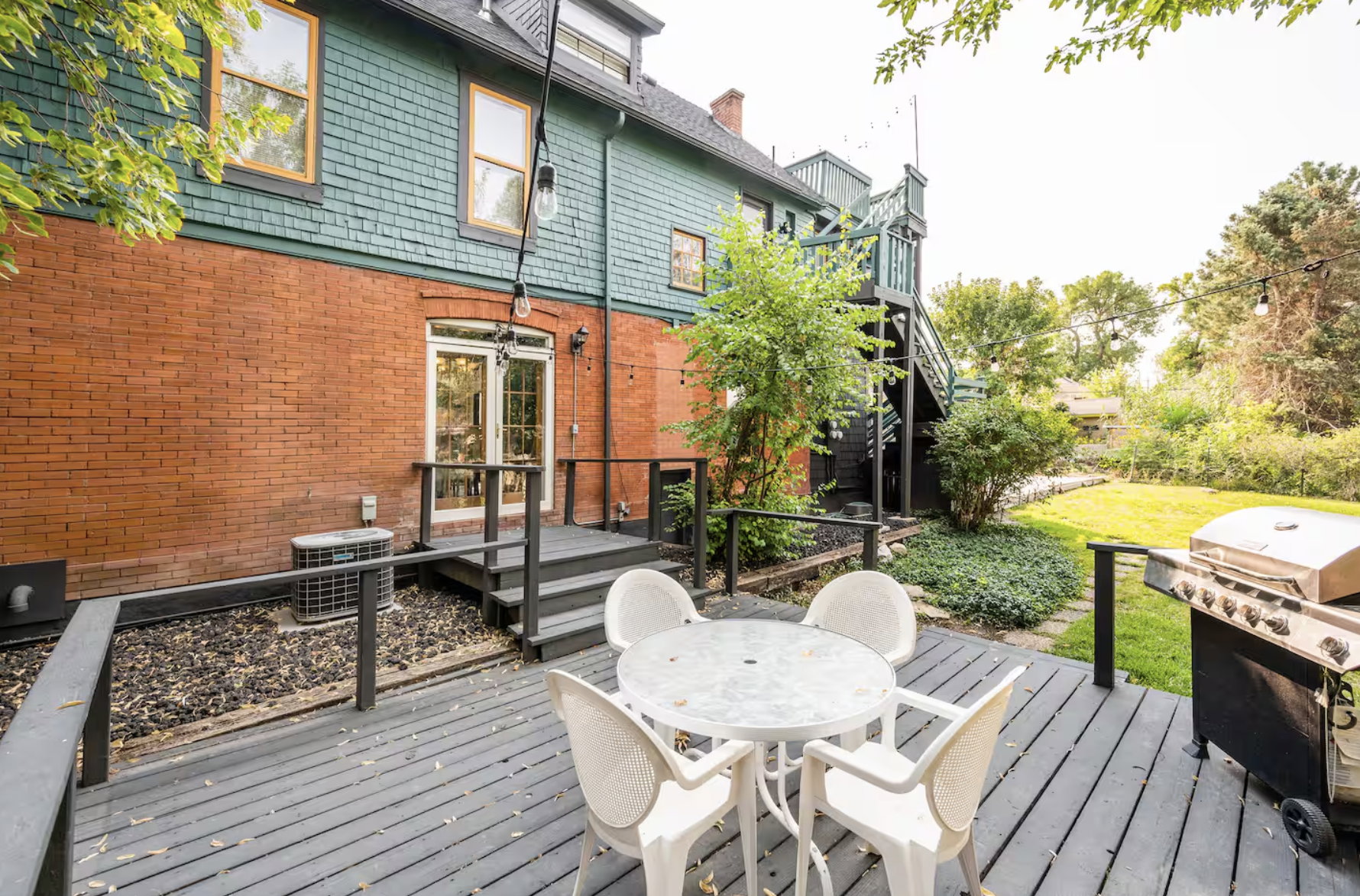 Wooden terrace featuring outdoor dining area, a grill, and a lawn
