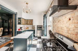 Kitchen featuring open shelves, a kitchen island, stainless steel gas range oven, dark floors, and a breakfast bar