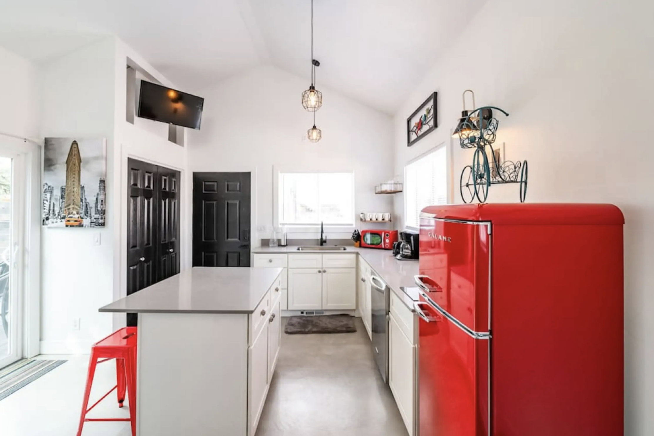 Kitchen featuring white cabinets, freestanding refrigerator, lofted ceiling, a kitchen breakfast bar, and pendant lighting
