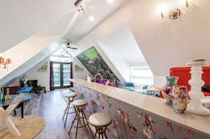 Bar featuring light wood-type flooring, light countertops, french doors, healthy amount of natural light, and lofted ceiling