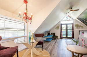 Dining room with wood-type flooring, french doors, vaulted ceiling, ceiling fan, and a chandelier
