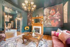 Living room with hanging lights, wood finished floors, a premium fireplace, and crown molding