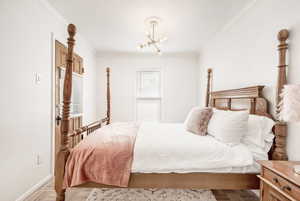 Bedroom with parquet flooring, ornamental molding, and hanging lights