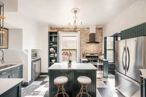 Kitchen featuring stainless steel appliances, light floors, a kitchen island, green cabinetry, and a chandelier