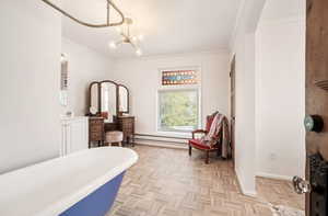 Bathroom featuring parquet flooring, a freestanding bath, vanity, hanging lights, and ornamental molding