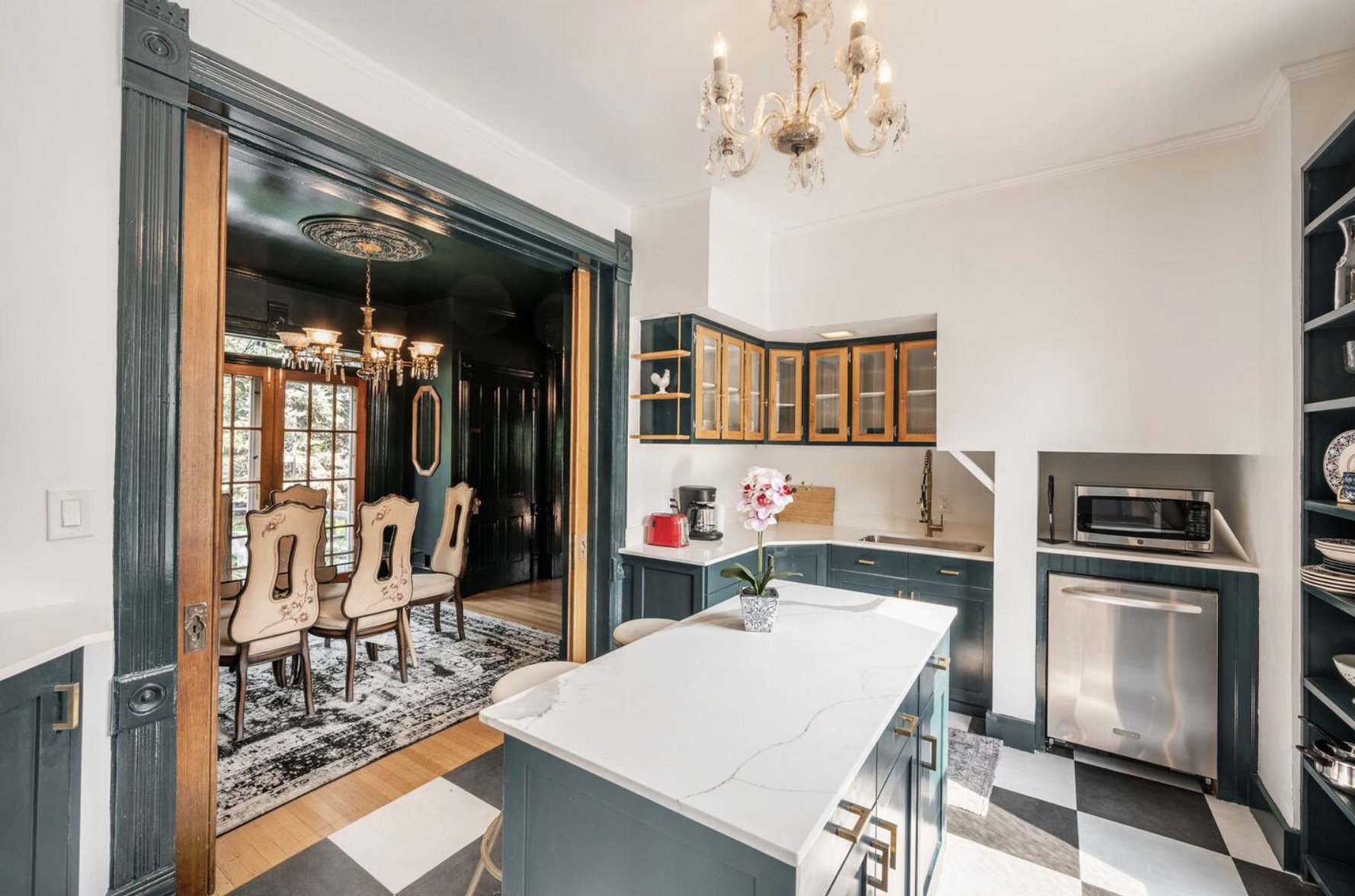 Dual tone kitchen with open shelves, a chandelier, stainless steel appliances, a center island, and light stone countertops