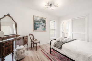 Bedroom with light wood-style floors, hanging lights, and crown molding