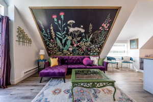 Living area with light wood finished floors and baseboard heating