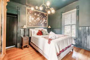 Bedroom featuring wainscoting, crown molding, and hardwood / wood-style floors