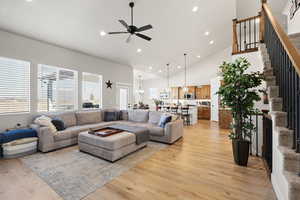 Living area with a ceiling fan, light wood-style flooring, suspended lighting, and lofted ceiling