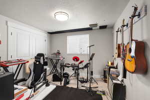Workout area with a textured ceiling and light colored carpet