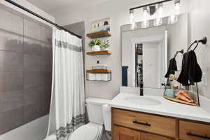 Full bath featuring vanity, shower / bath combo, and a textured ceiling