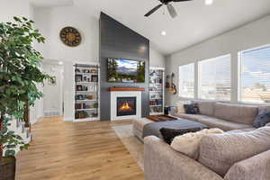 Living room featuring vaulted ceiling, light wood finished floors, a fireplace, recessed lighting, and a ceiling fan