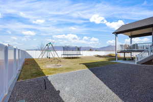 Fenced backyard featuring a patio, a mountain view, a playground, and a trampoline