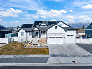 Modern farmhouse with a gate, stone siding, and solar panels