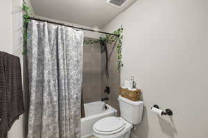 Full bath featuring toilet and shower / tub combo with curtain