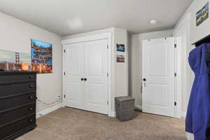 Bedroom with light carpet, a closet, and a textured ceiling