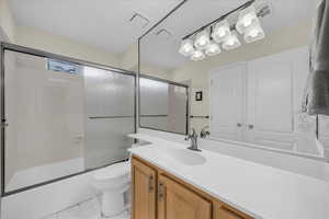 Full bath with vanity and bath / shower combo with glass door