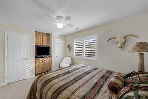 Bedroom featuring ceiling fan, a textured ceiling, and light carpet