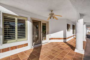 Doorway to property featuring ceiling fan and stucco siding