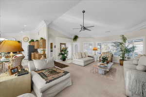Living room with a ceiling fan, crown molding, light carpet, lofted ceiling, and arched walkways