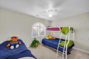 Carpeted bedroom featuring a textured ceiling and a ceiling fan