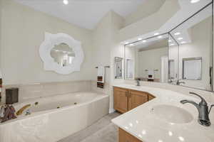 Bathroom with double vanity, a tub with jets, and recessed lighting
