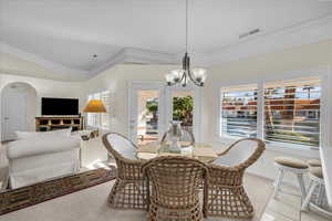 Dining space featuring light colored carpet, hanging lights, arched walkways, and lofted ceiling