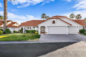 Mediterranean / spanish home with stucco siding, a front yard, driveway, and a tiled roof
