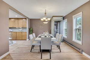 Dining area with baseboard heating, suspended lighting, and light wood-style floors