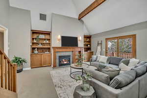 Living room with light carpet, vaulted ceiling, and a tile fireplace